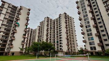 A residential building complex with multiple high-rise apartments, a tennis court, and a basketball court.