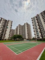 A residential building complex with multiple high-rise apartments, a tennis court, and a basketball court.
