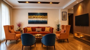 A modern living room with a sofa, two armchairs, a coffee table, and a flat-screen TV. - Krishnabhumi Holydays (Mathura)