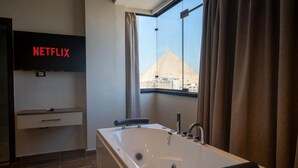 Une salle de bain moderne avec une grande baignoire, un logo Netflix et une vue sur une pyramide.