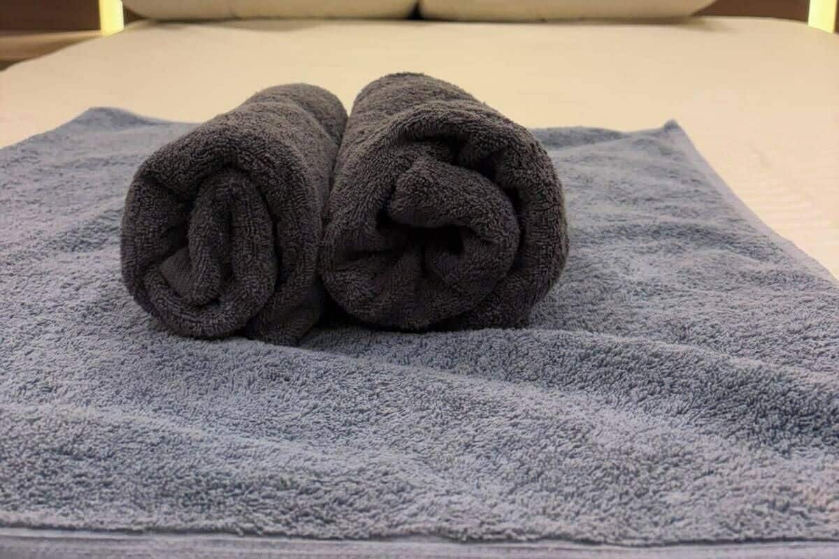 A neatly made bed with a rolled towel in the center, two pillows, and a wall with ancient Egyptian hieroglyphs.
