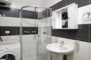 Ein modernes Badezimmer mit einer Duschkabine aus Glas, einem weißen Waschbecken und einem eingebauten Schrank.