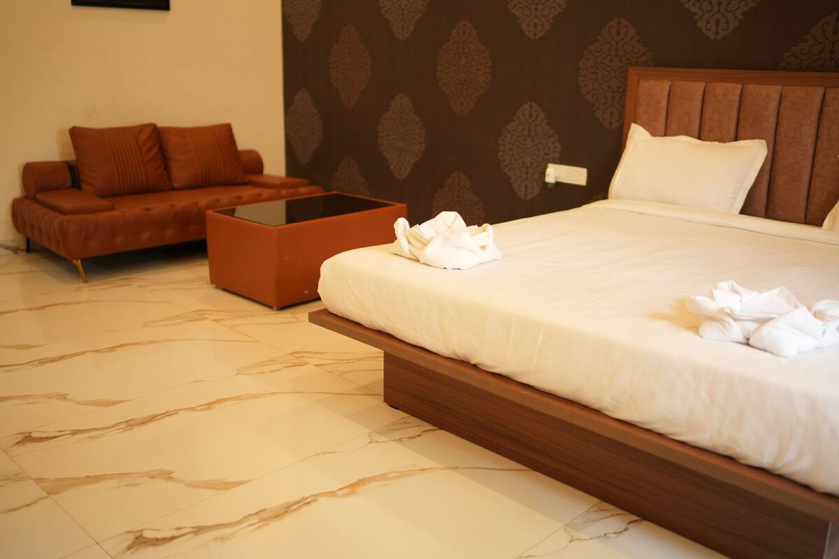 Habitación de hotel con cama, sofá, mesa de centro y pared estampada.