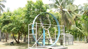 A large metal sculpture in an outdoor park setting with trees and a clear sky.