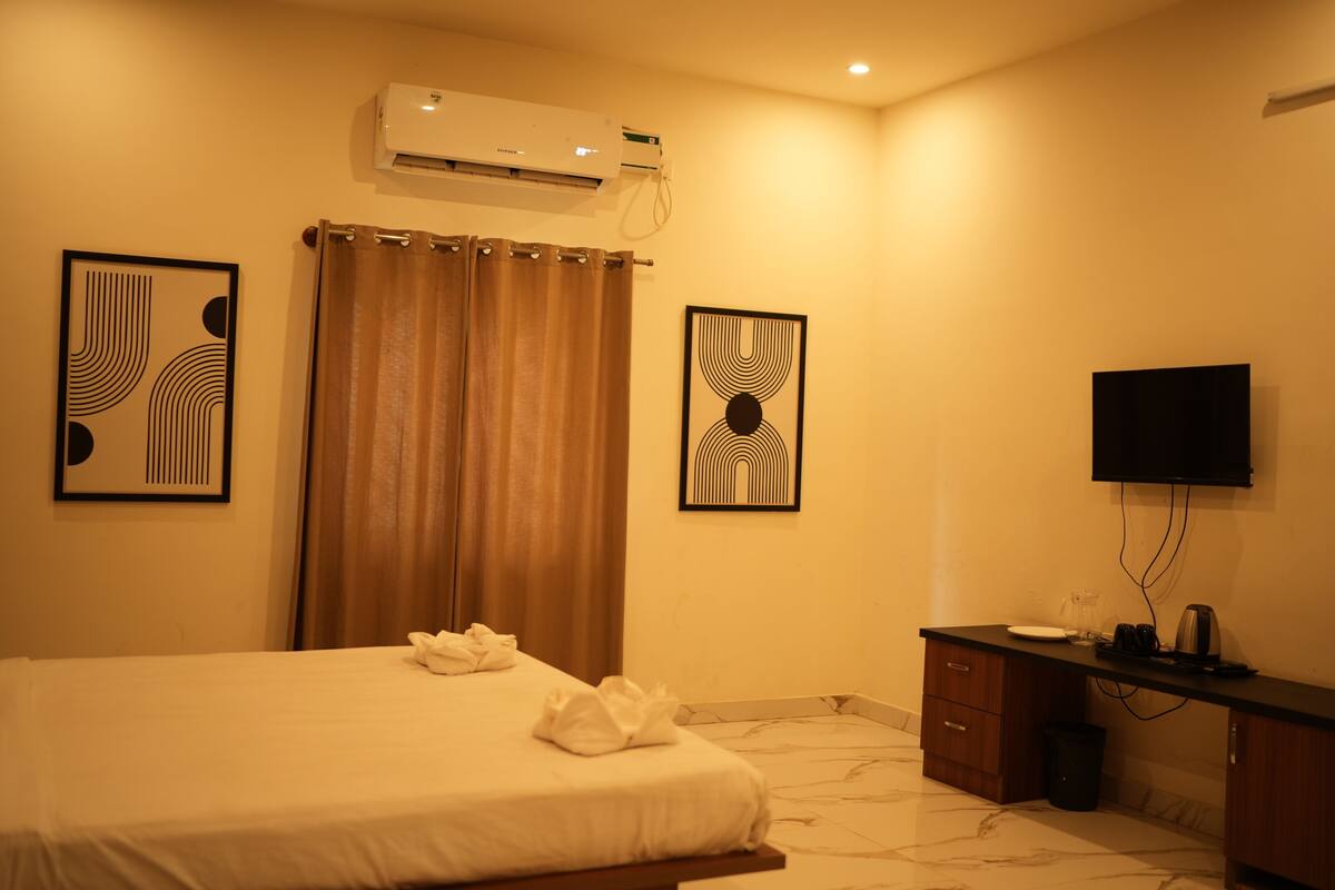 Habitación de hotel con cama, escritorio, televisor y dos obras de arte enmarcadas.