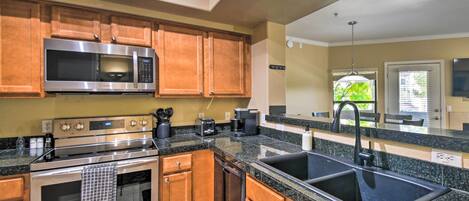 A kitchen with wooden cabinets, a stainless steel microwave, a double sink, and a built-in oven.