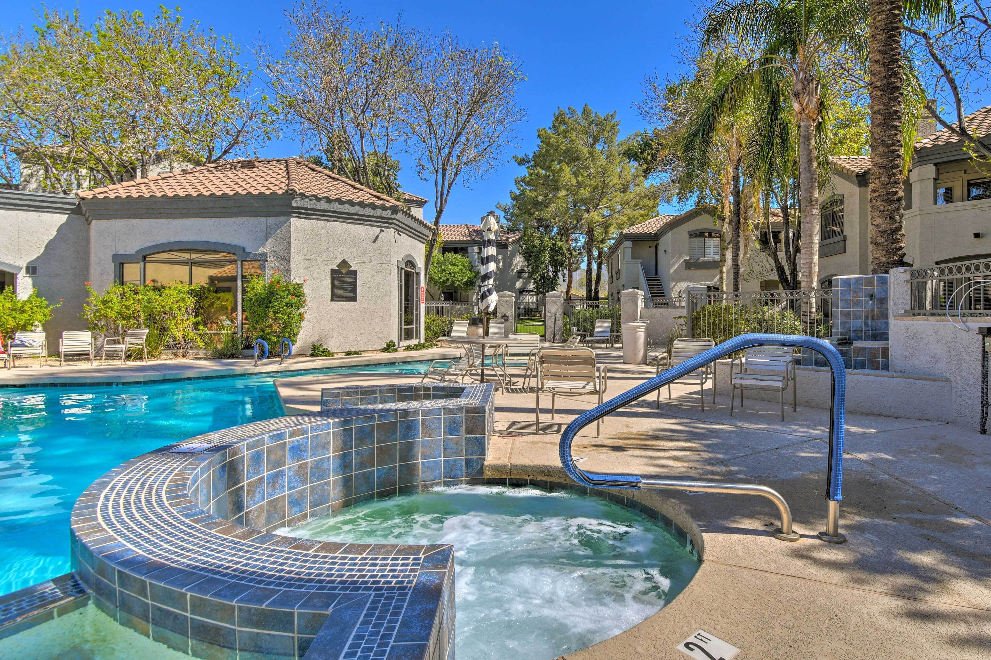 A swimming pool with a hot tub, lounge chairs, and a covered patio area.