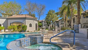 Una piscina con jacuzzi, sillas de descanso y un patio cubierto.