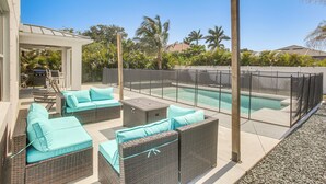 Eine Terrasse im Freien mit Korbmöbeln, einem Pool und einer überdachten Sitzgelegenheit.