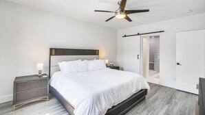 Ein Schlafzimmer mit Bett, Nachttischen, Deckenventilator und einer Schiebetür.