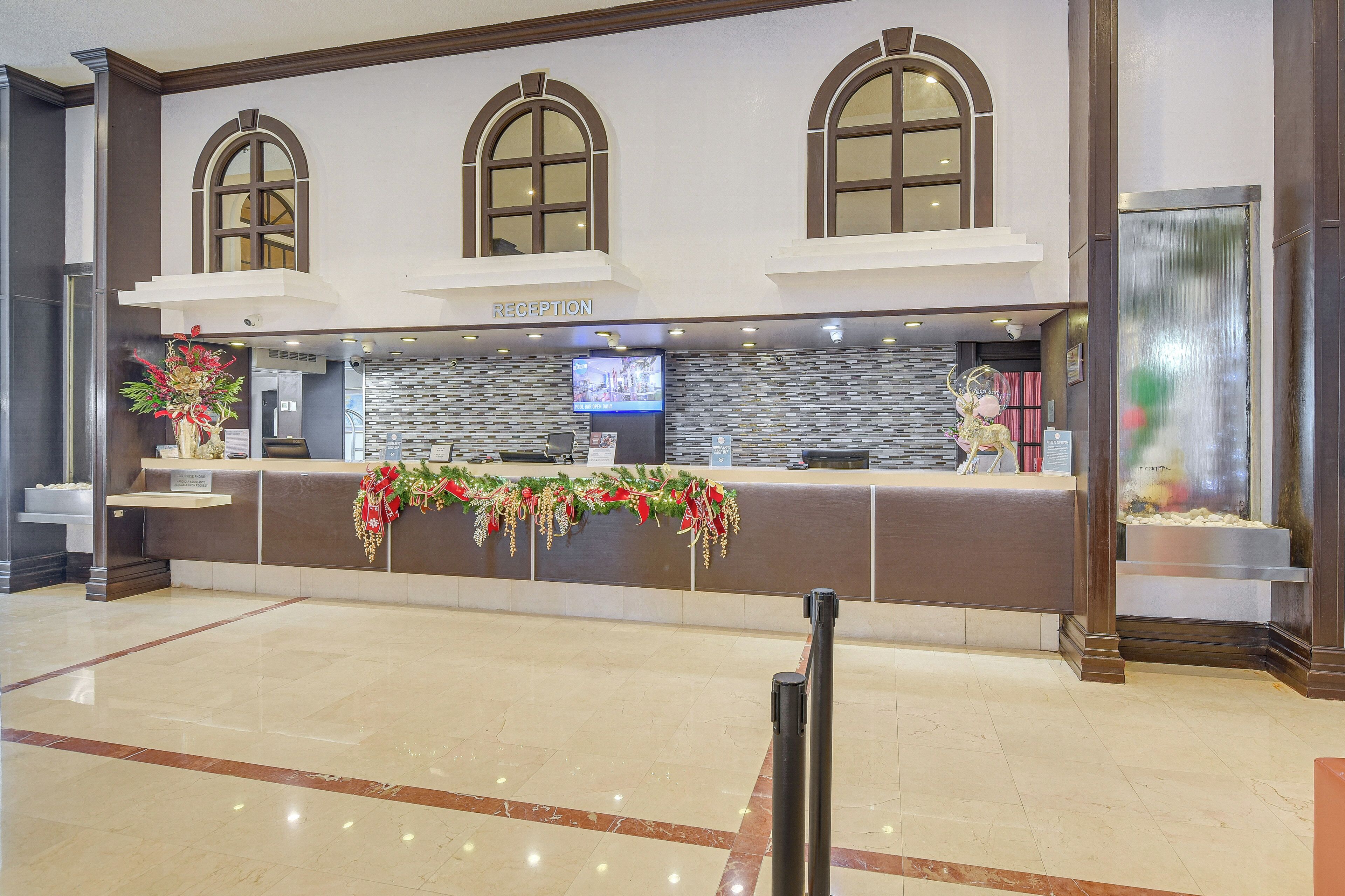 A reception area with a reception desk, a television, and a decorative garland.