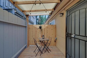 Un patio techado con una mesa y sillas, cerca de madera y puerta de garaje.