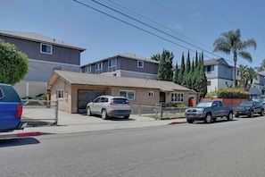 Una calle residencial con casas, coches aparcados y cielo despejado.