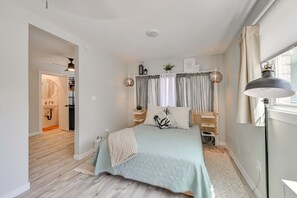 A bedroom with a bed, bedside tables, a window with curtains, a hanging lamp, and a view of a hallway. - 1 Mi to Military Base: Cozy Imperial Beach Studio (Imperial Beach)