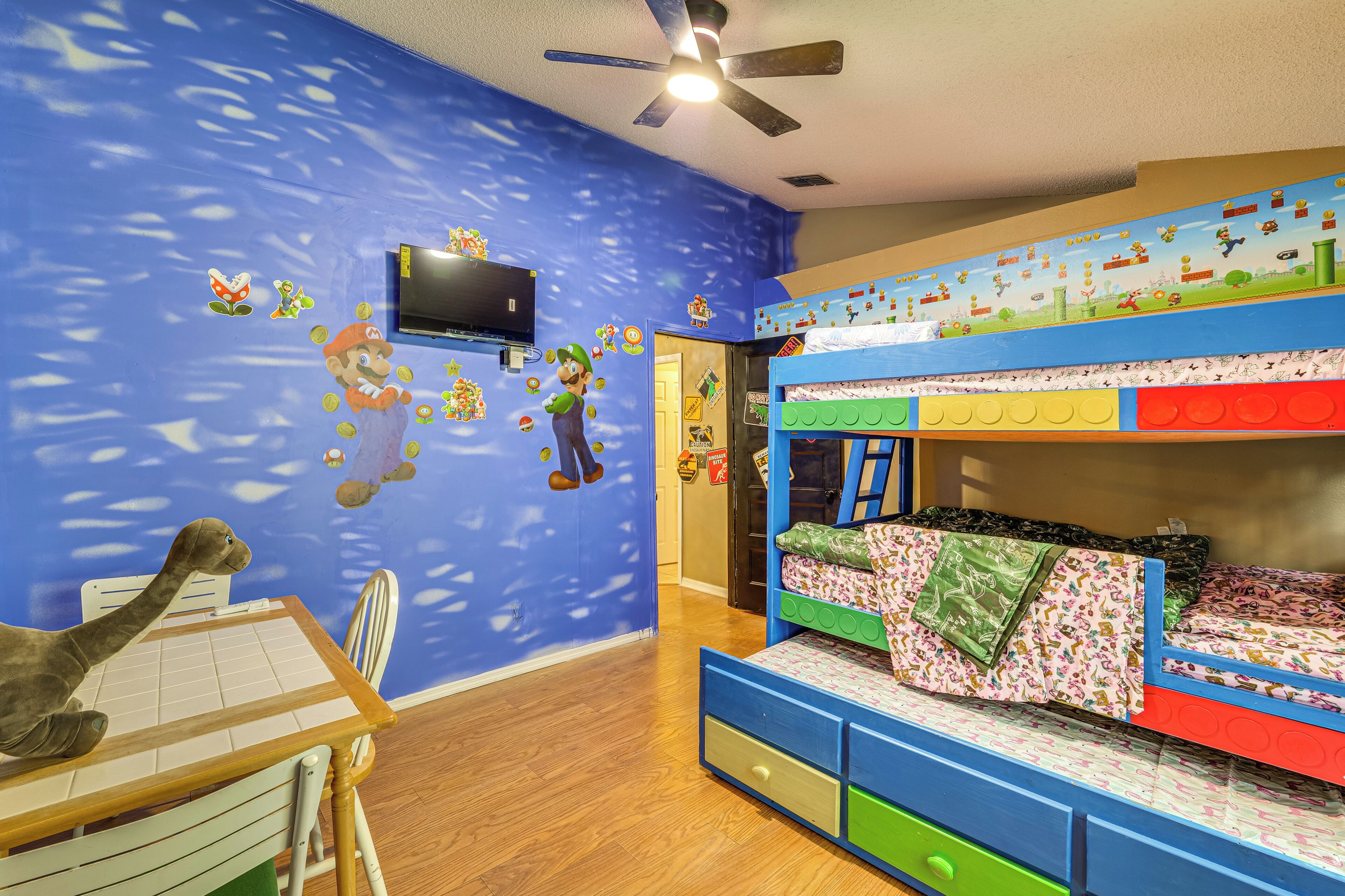 Quarto de criança com beliche, escrivaninha e ventilador de teto.