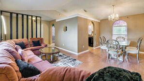 A spacious living room with a sectional sofa, a dining area with a table and chairs, and a staircase. - Themed Interior, Poolside Fun! Villa Near Disney (Davenport)