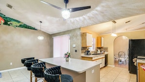 A kitchen with a bar area, a ceiling fan, and a refrigerator. - Themed Interior, Poolside Fun! Villa Near Disney (Davenport)
