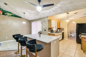 A kitchen with a bar area, a ceiling fan, and a refrigerator. - Themed Interior, Poolside Fun! Villa Near Disney (Davenport)