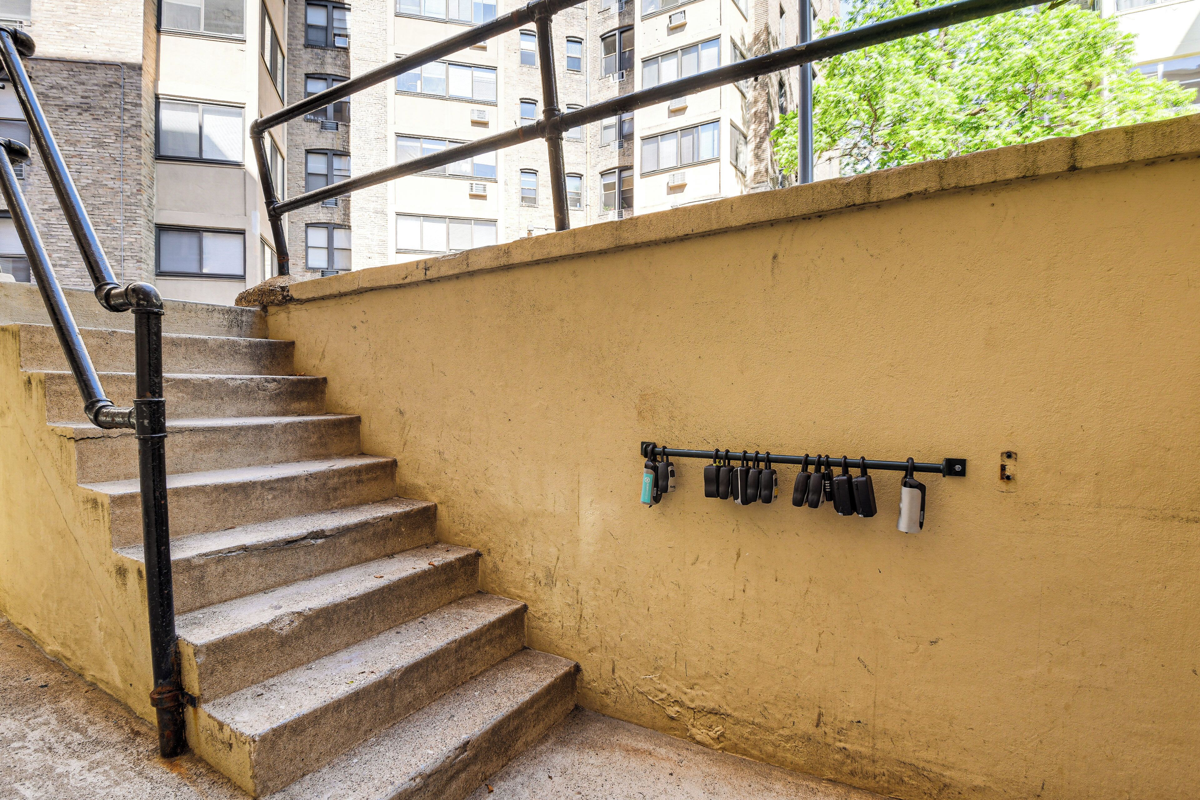 Una escalera de concreto con barandillas de metal, una pared amarilla y una fila de llaves negras y blancas colgadas en la pared.