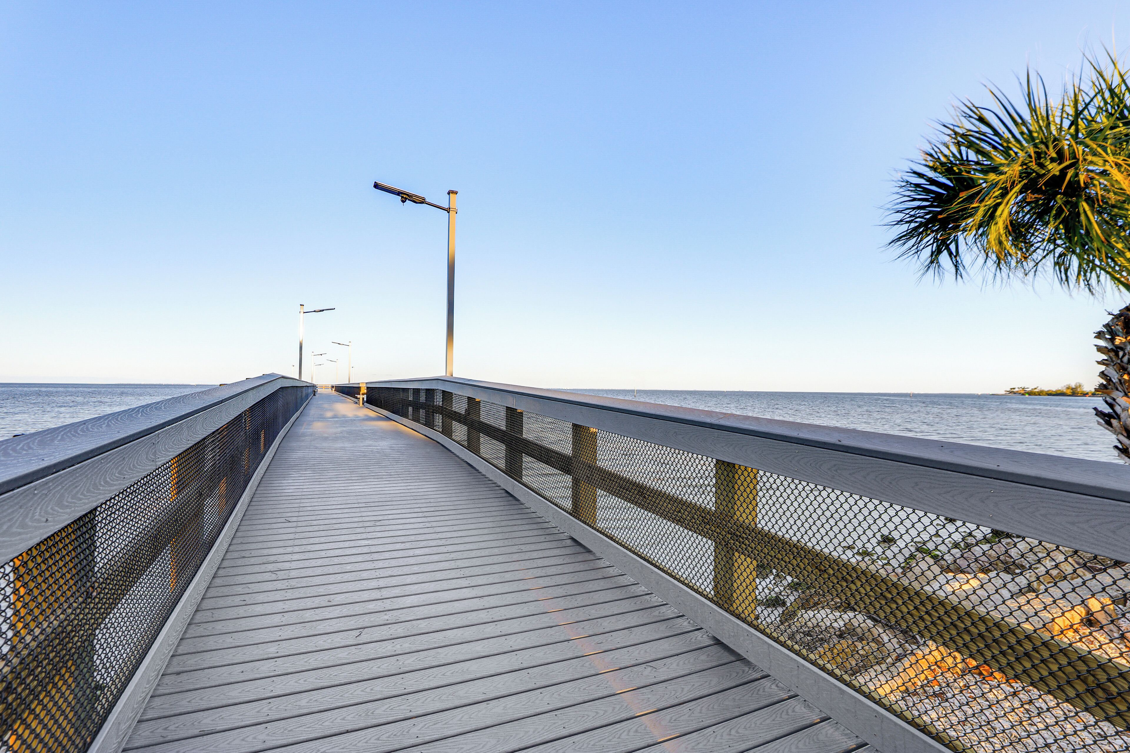 A wooden pier extending into calm waters, with a clear sky above.