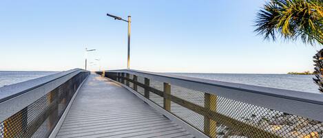 A wooden pier extending into calm waters, with a clear sky above.