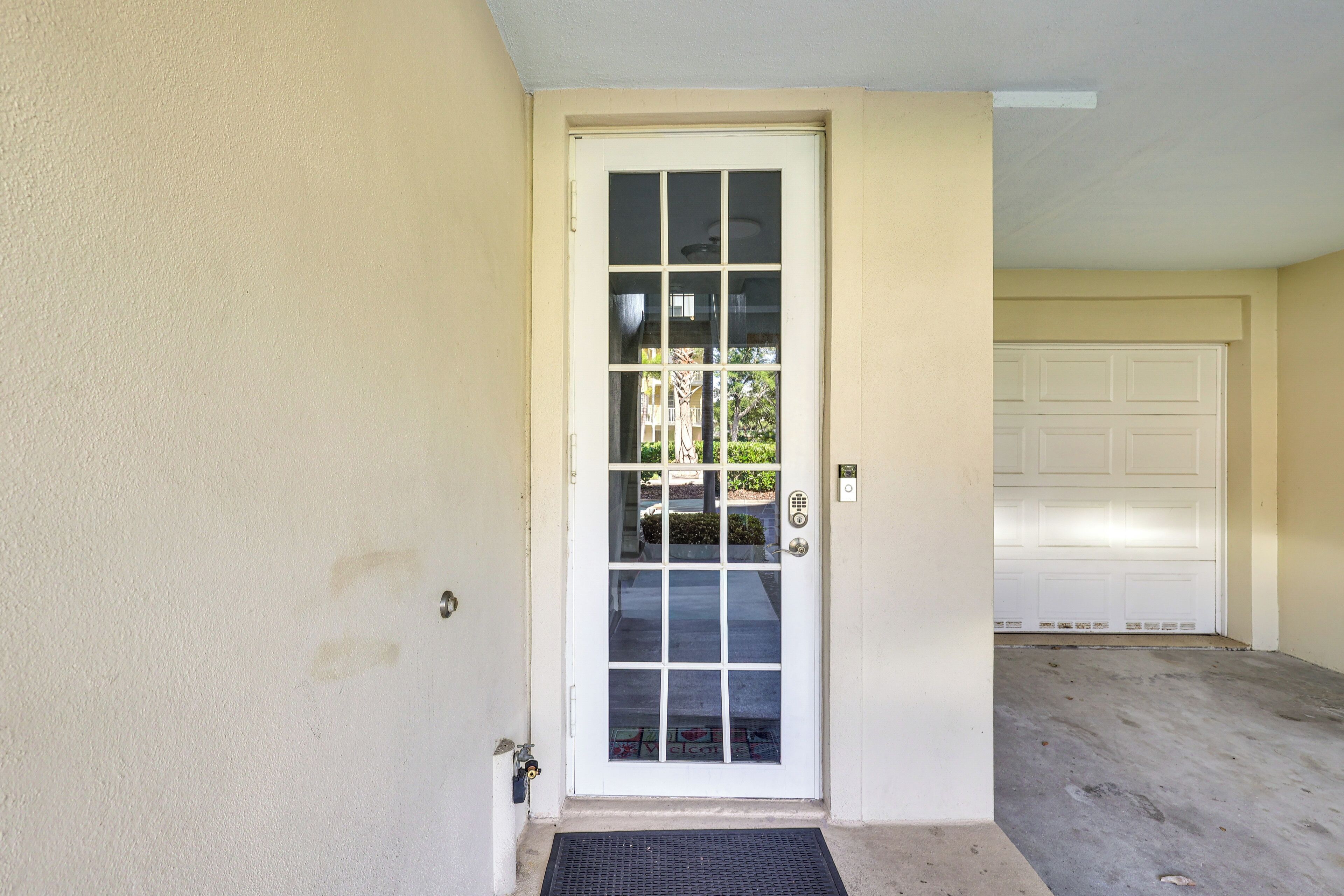 A white door with a glass panel, a garage door in the background, and a concrete floor.
