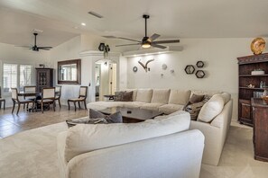 Ein geräumiges Wohnzimmer mit einem großen Ecksofa, einem Couchtisch und einem Deckenventilator.