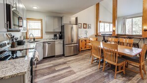 A modern kitchen with stainless steel appliances, wooden dining table, and chairs. - Ski-in/ski-out! Modern Mountainside Stay in Granby (Granby)