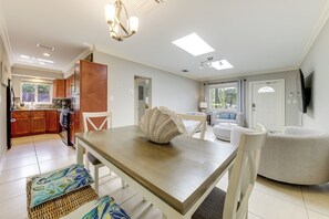 Eine moderne Küche mit Holzausbau, einem Esstisch mit Stühlen und einer Wohnbereich mit Sofa und Fernseher.