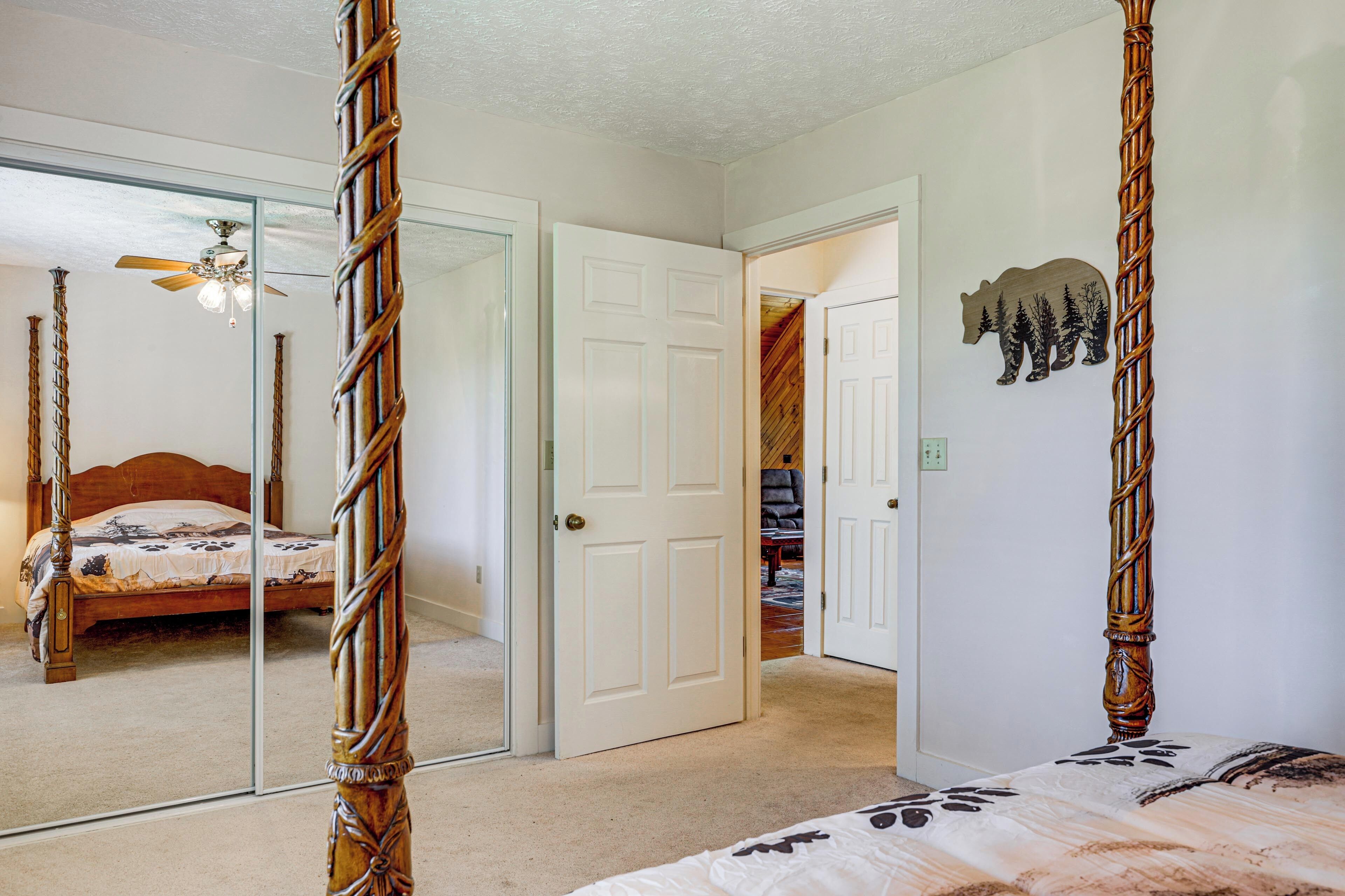 A bedroom with a four-poster bed, a large mirror, and a door leading to another room.