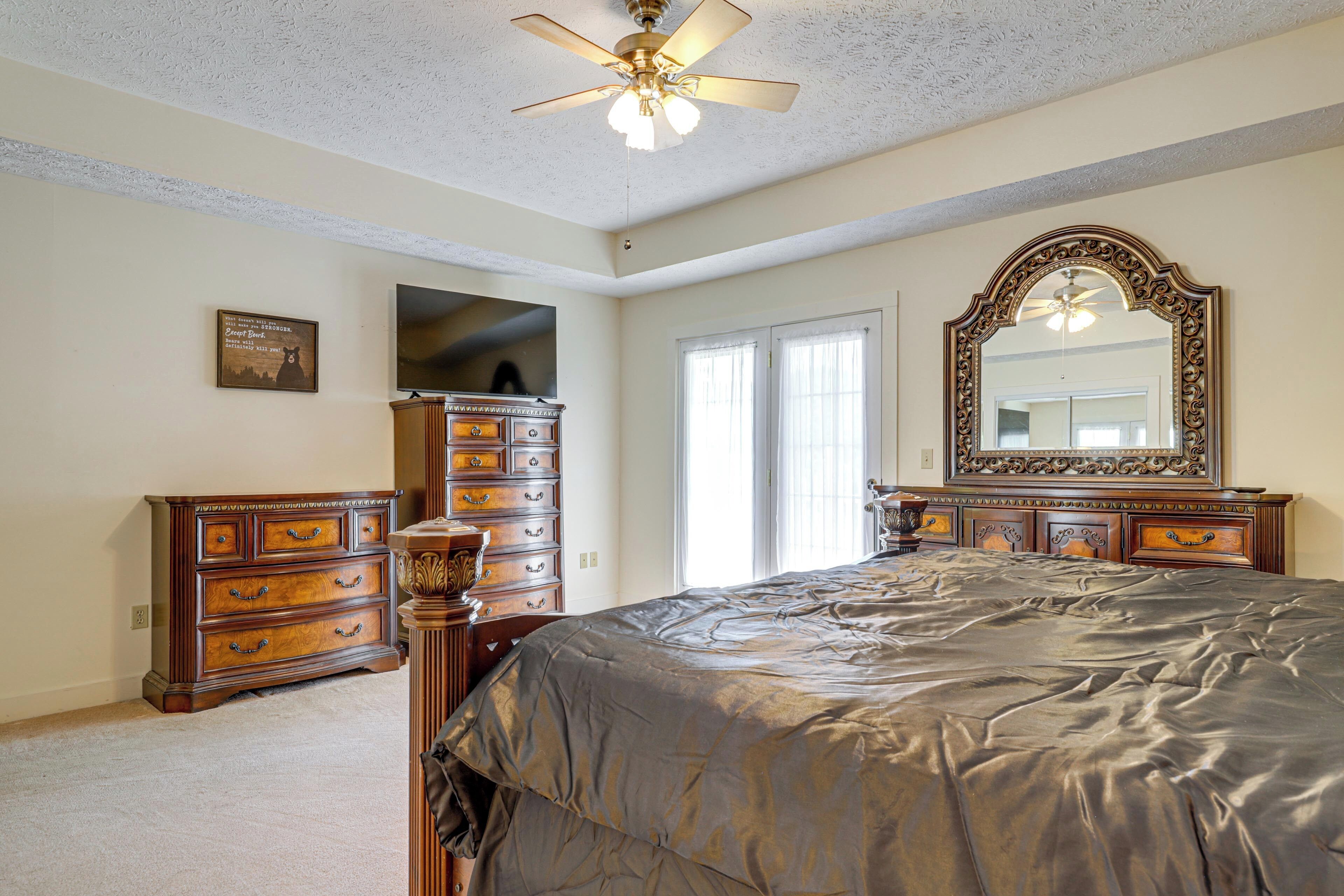 Une chambre à coucher avec un grand lit, une commode, un téléviseur et un ventilateur de plafond.
