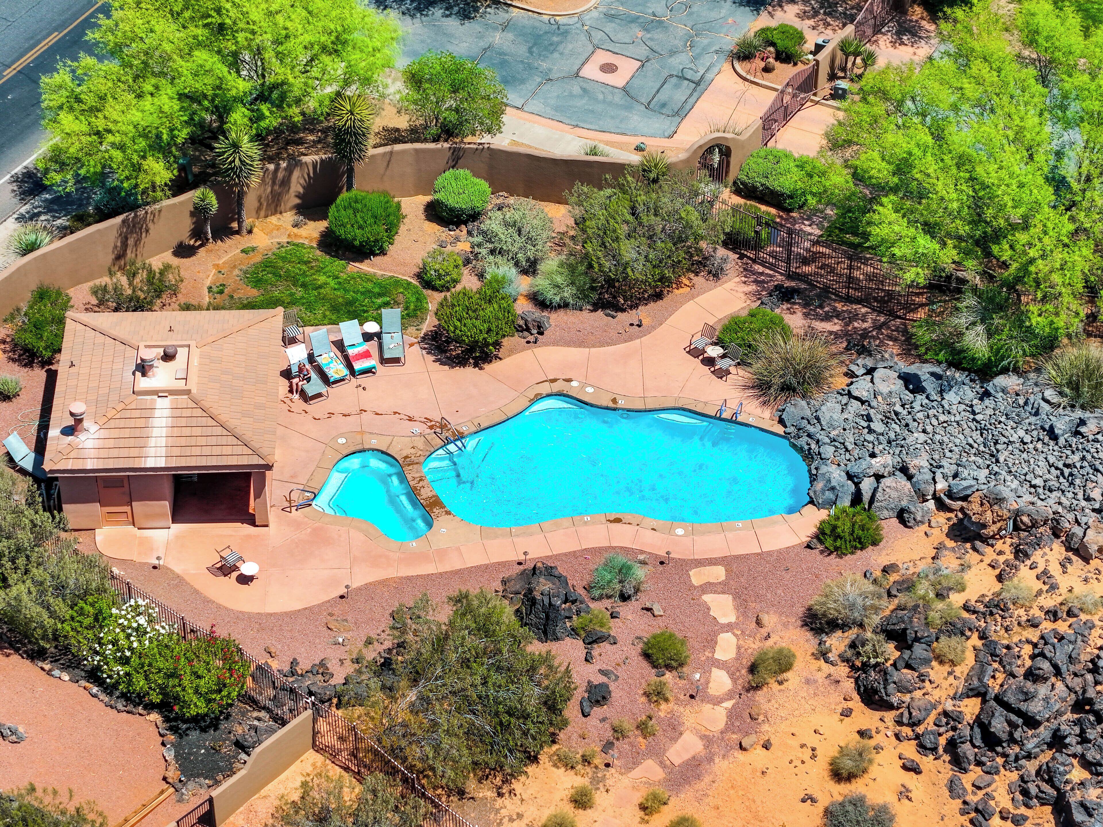 Vista aérea de una propiedad residencial con piscina, sillones de descanso y un porche cubierto.