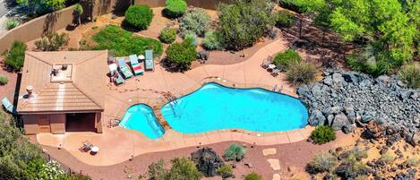 Vista aérea de una propiedad residencial con piscina, sillones de descanso y un porche cubierto.