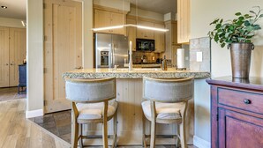 A kitchen with wooden cabinets, a stainless steel refrigerator, a microwave, and a granite countertop. - Pool & Hot Tub Access! Gated Santa Clara Getaway (Santa Clara)