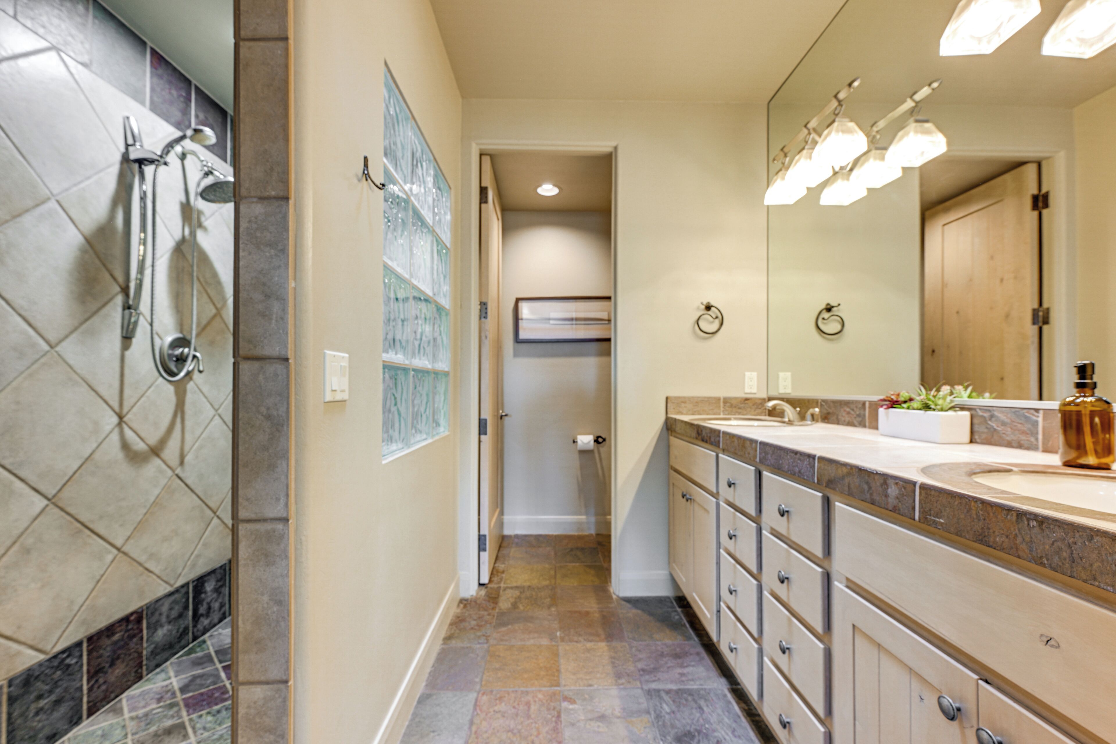 A modern bathroom with a shower, a large mirror, and a vanity with a sink.