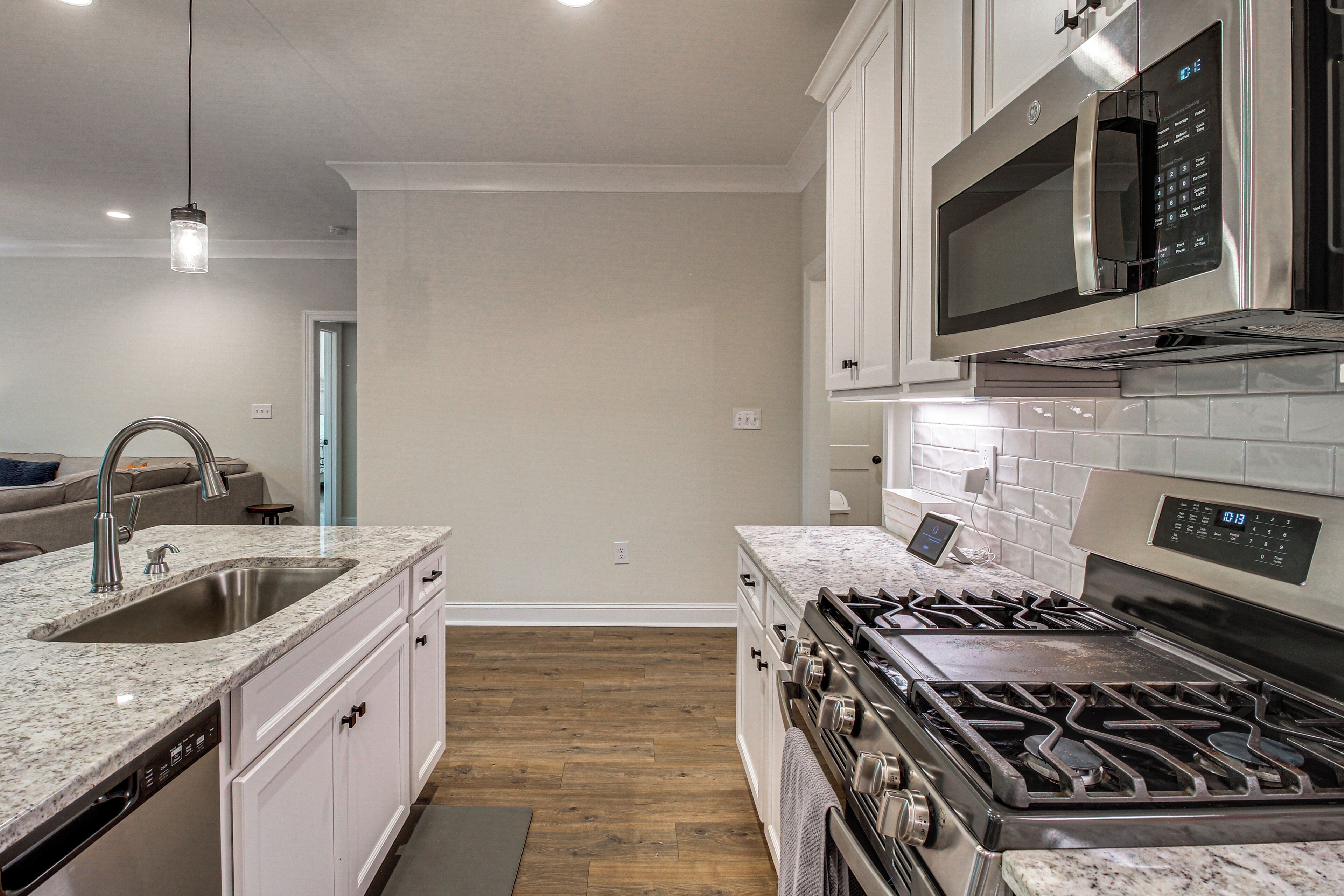 A modern kitchen with a stainless steel stove, a built-in microwave, and a granite countertop.