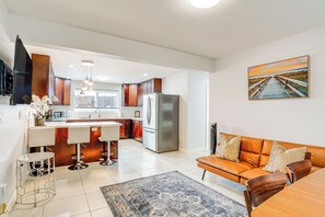 A modern kitchen with a central island, a dining area with a wooden table, and a living room with a sofa. - Walk to Sand! Ewa Beach Group Retreat (Ewa Beach)