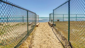 Un camino que lleva a una playa, con una cerca de malla en ambos lados.