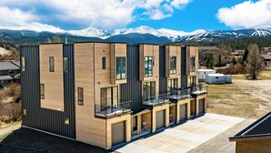 A modern multi-story building with a flat roof, large windows, and a balcony. - On Fraser River w/ Trail Access! Mtn-view Unit (Fraser)