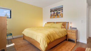 A bedroom with a bed, a nightstand, a ceiling fan, a window, and a painting on the wall. - On Fraser River w/ Trail Access! Mtn-view Unit (Fraser)
