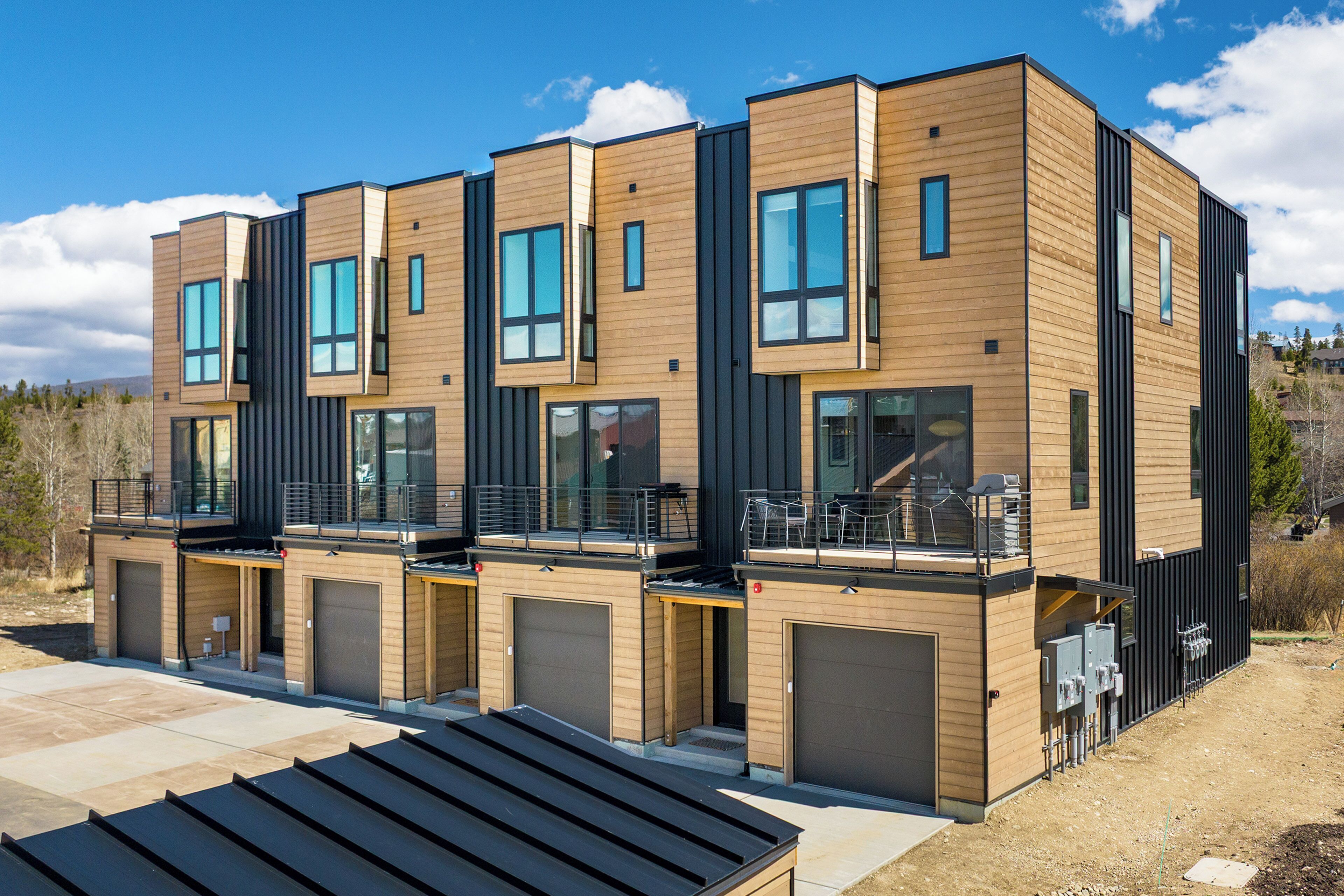 A modern multi-story residential building with large windows, balconies, and garage doors.