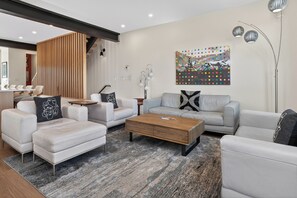 Ein modernes Wohnzimmer mit einer Couch, Sesseln, einem Couchtisch und einem dekorativen Gemälde.