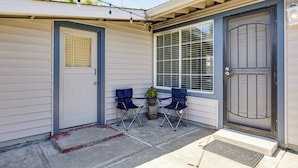 A house with a garage door, a front door, a window with blinds, and a small porch with two chairs and a potted plant. - Wfh-friendly Retreat w/ Office Near Silicon Valley (Hayward)