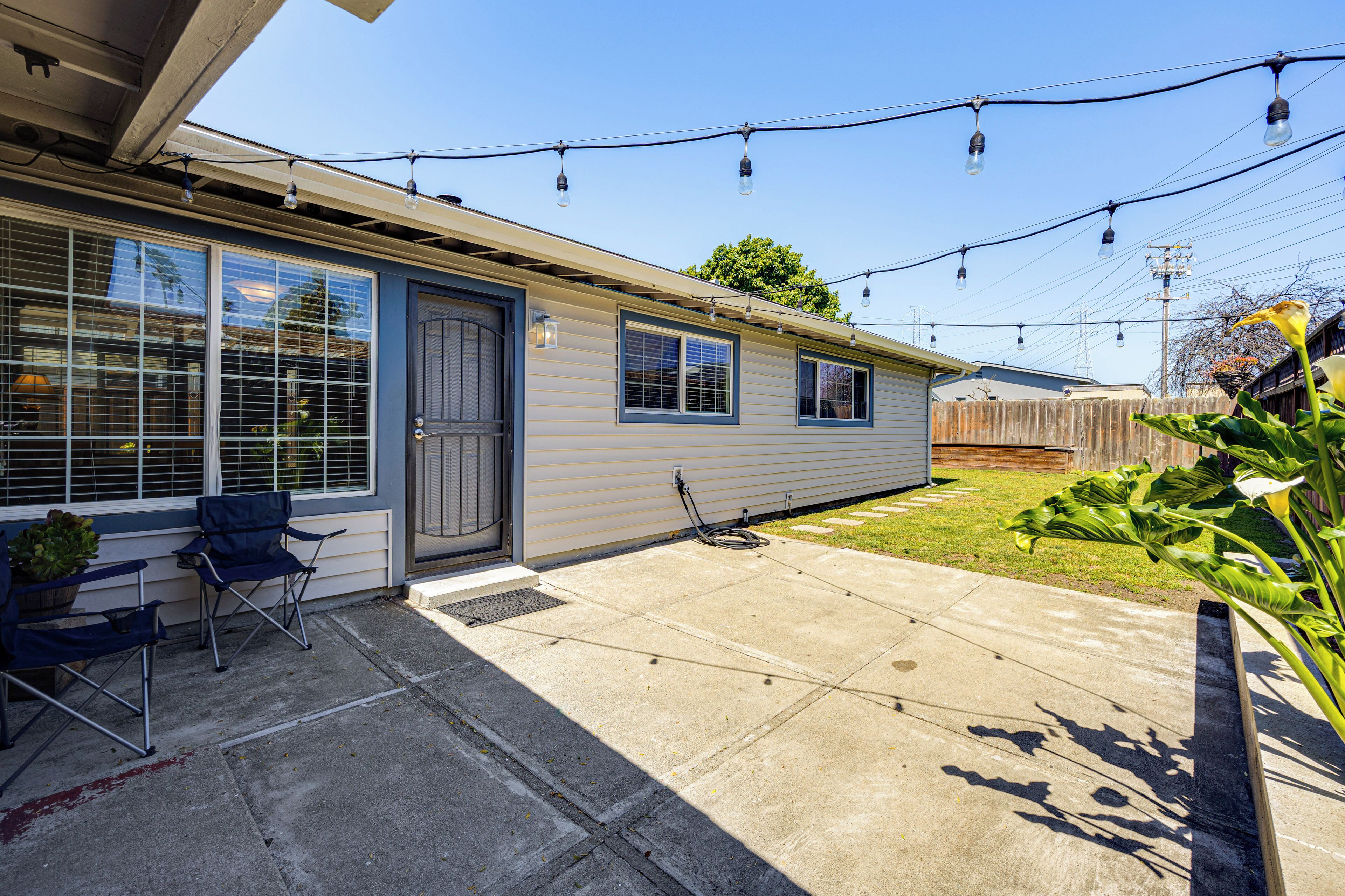 A single-story house with a covered patio, a small garden, and string lights.