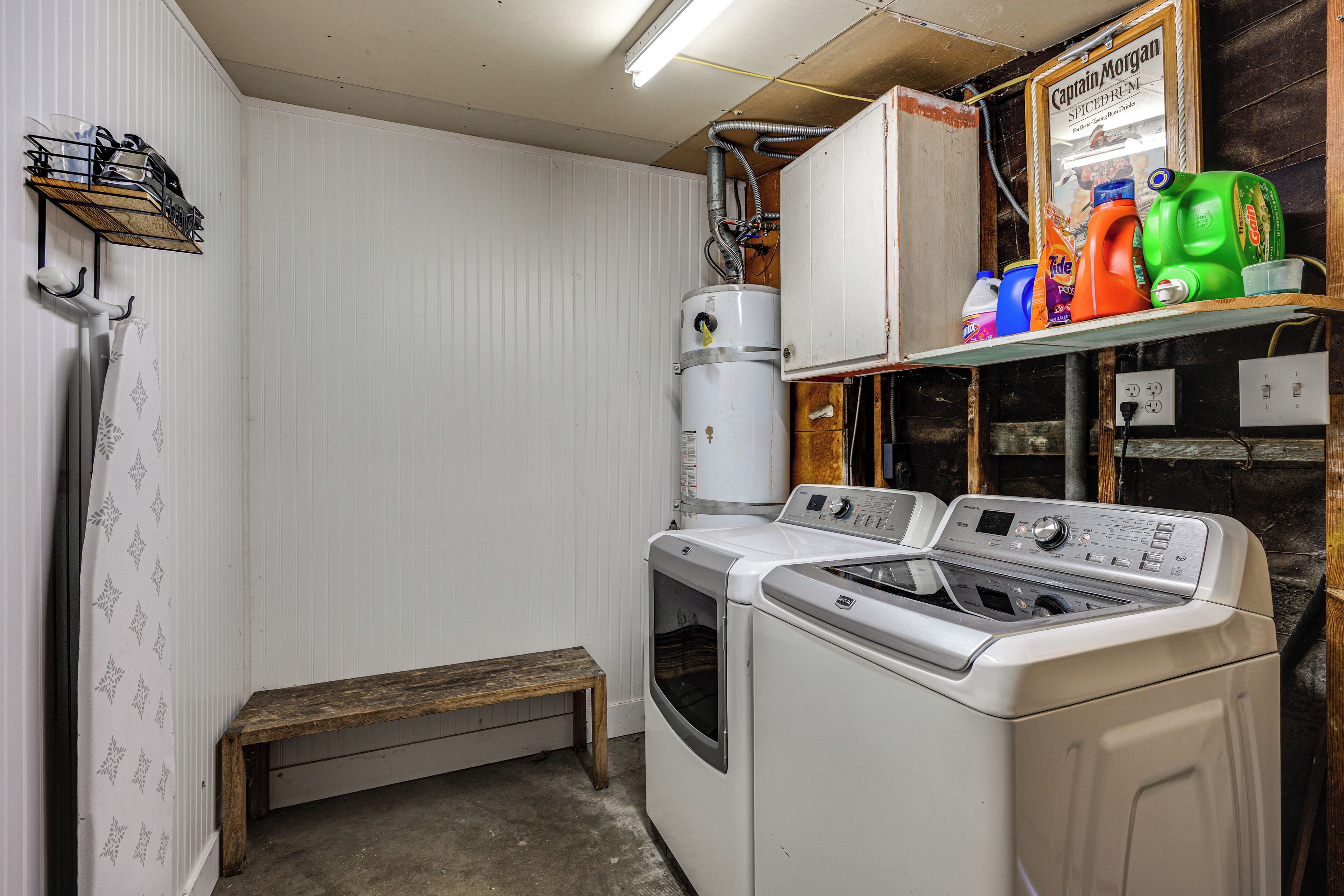 A laundry room with a washing machine, dryer, and a bench.