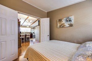 Ein Schlafzimmer mit Bett, einer Tür zu einer Küche und einem Essbereich.