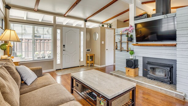 A living room with a fireplace, wooden beams, a sofa, and a coffee table. - Wfh-friendly Retreat w/ Office Near Silicon Valley (Hayward)