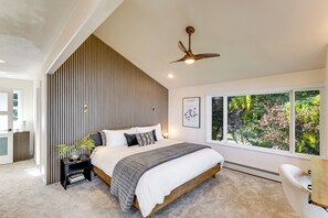 Quarto com cama, mesa de cabeceira, abajur, janela e ventilador de teto.