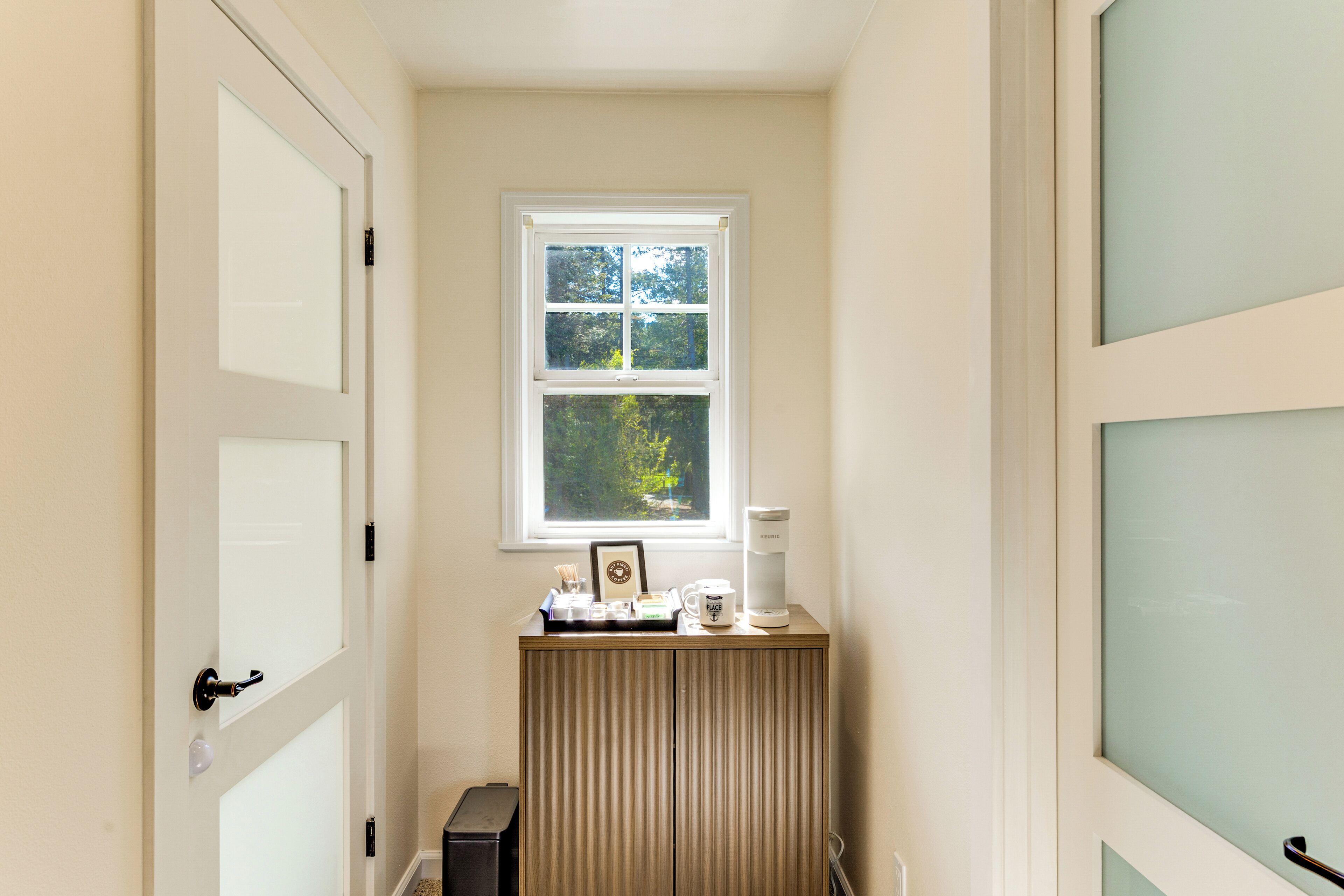 A small room with a window, a radiator, and a coffee maker on a counter.