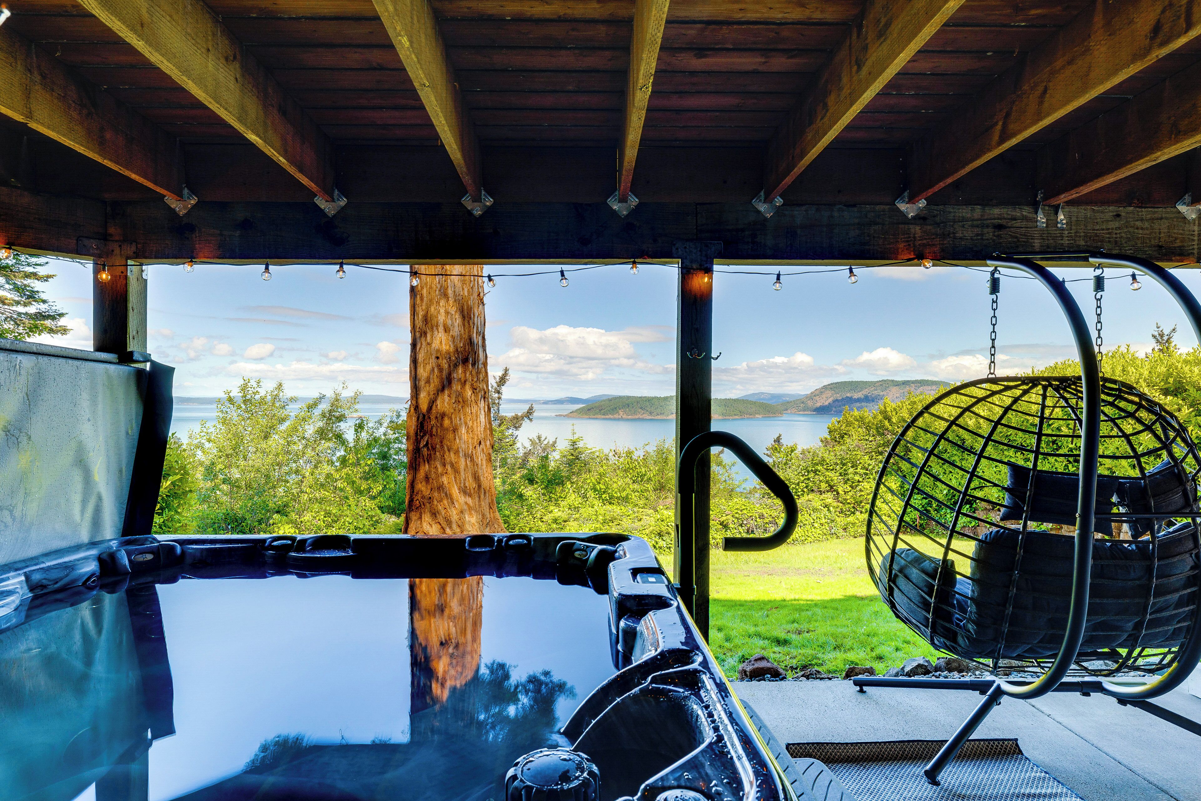 A vehicle with a view of a lake and mountains, a hanging chair, and a wooden structure.